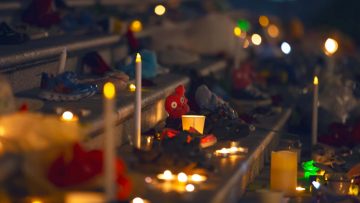Candles, toys, and children's shoes lining stairs in memorial